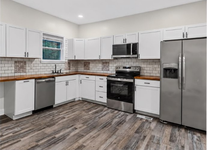 After: Full kitchen rebuild — cabinets, butcher-block counters, tile and appliances.