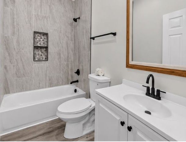 After: New bath — tile surround, tub, toilet, vanity and plumbing.